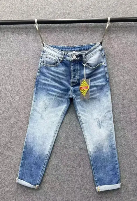 Jean homme en denim bleu délavé avec des effets de blanchiment progressifs, déchirures discrètes et finitions légèrement usées.